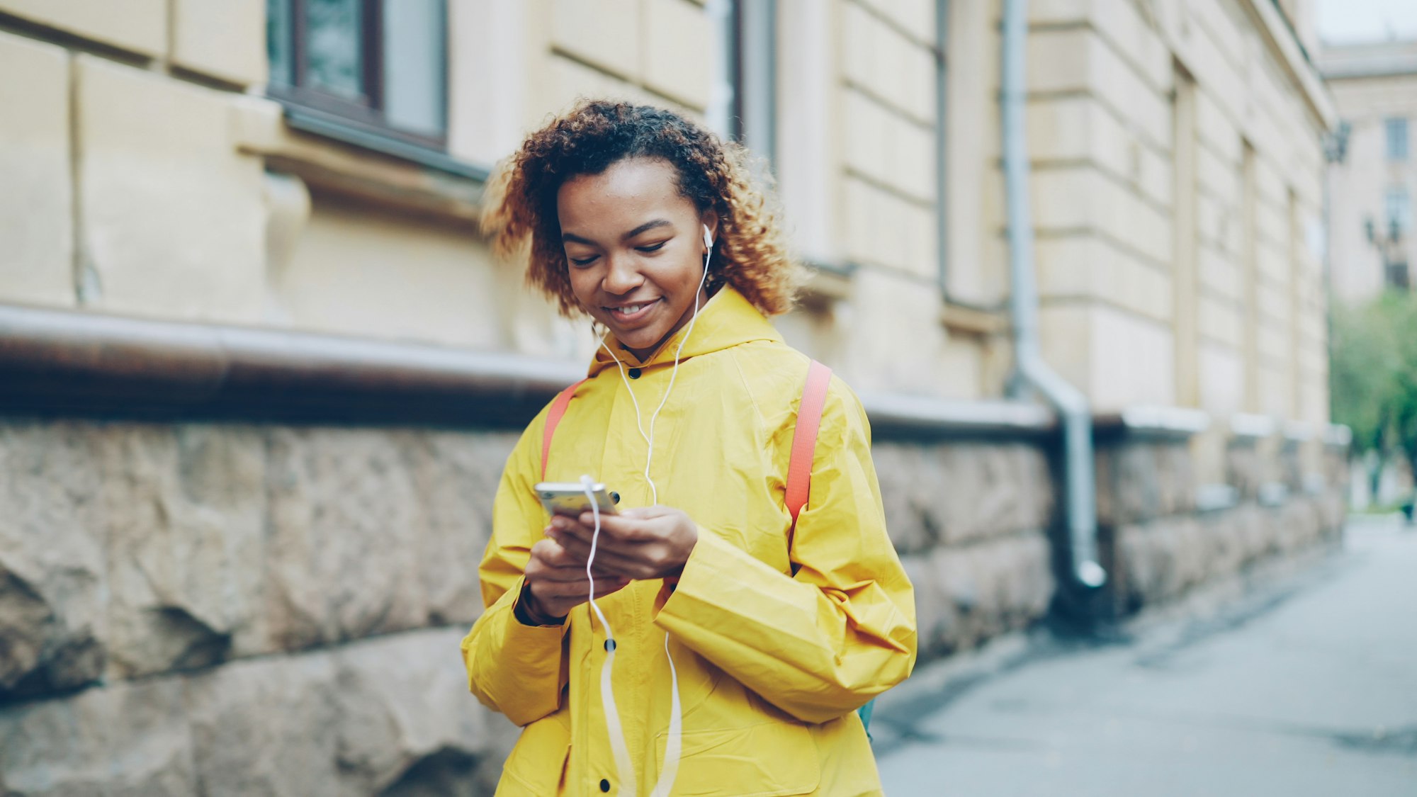 A woman smiling as she checks a message on her phone