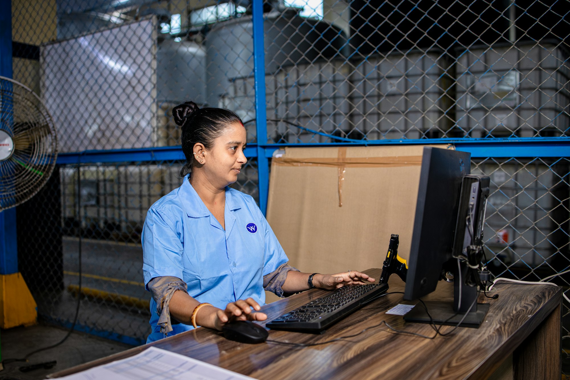A logistics coordinator reviewing orders at a computer in a warehouse